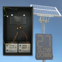 Solar Power Option Inside of an LED speed sign with 2 batteries and a solar charge controller inside. In the background is a sign with a solar panel