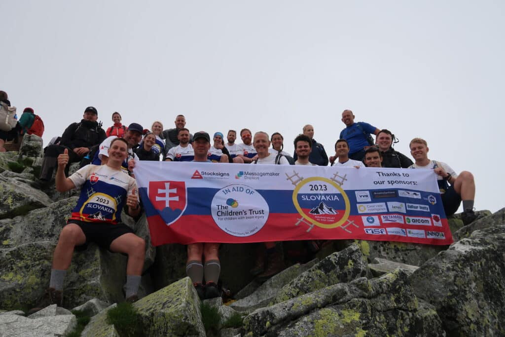 Messagemaker team and friends posing with the charity banner atop mount Rysy